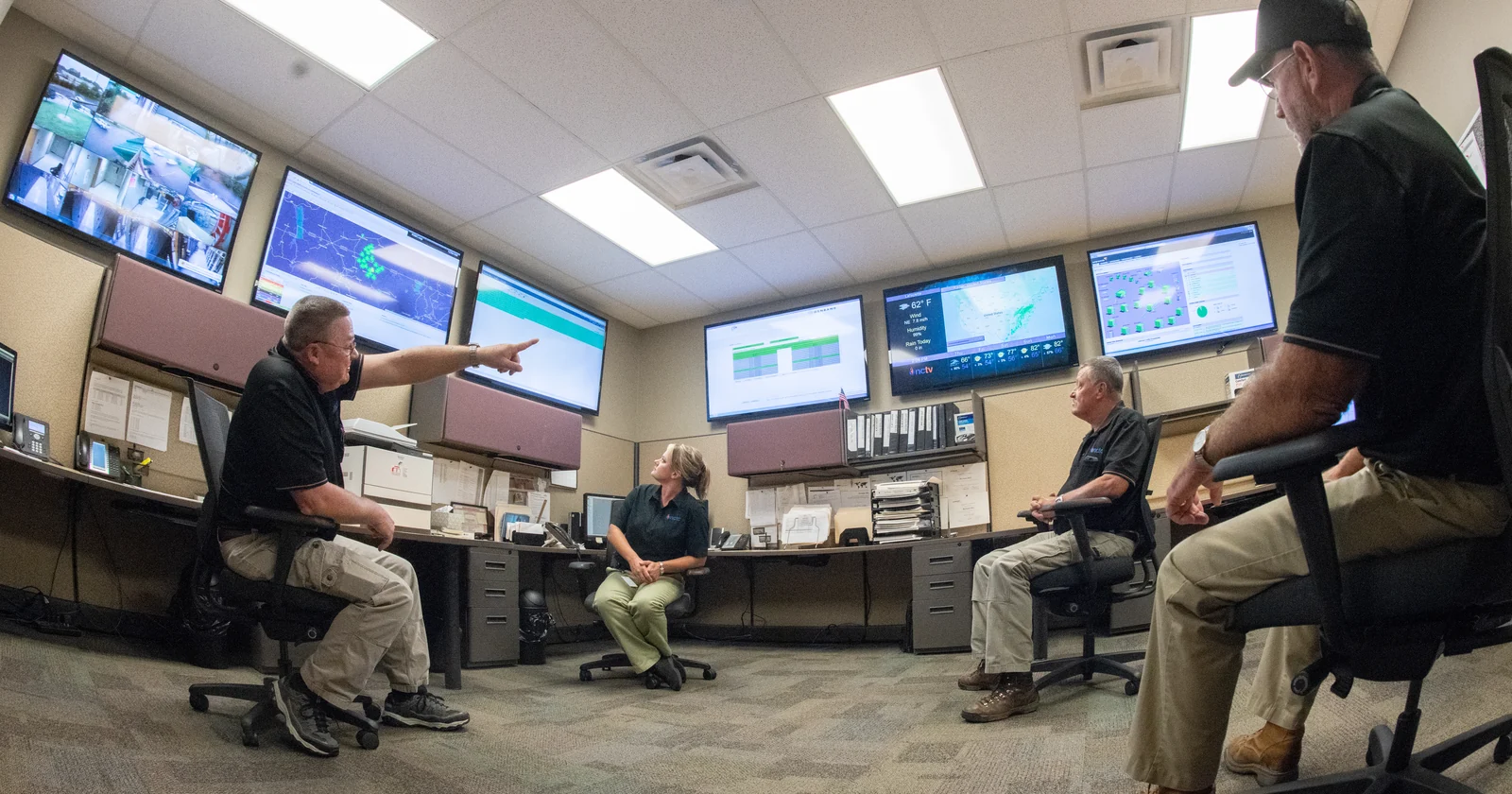 Technicians monitoring network operations on wall mounted screens
