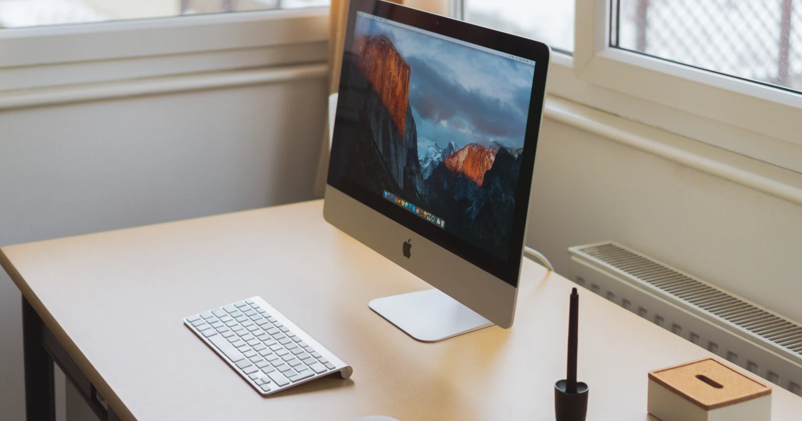 Desktop computer on a desk beside a window