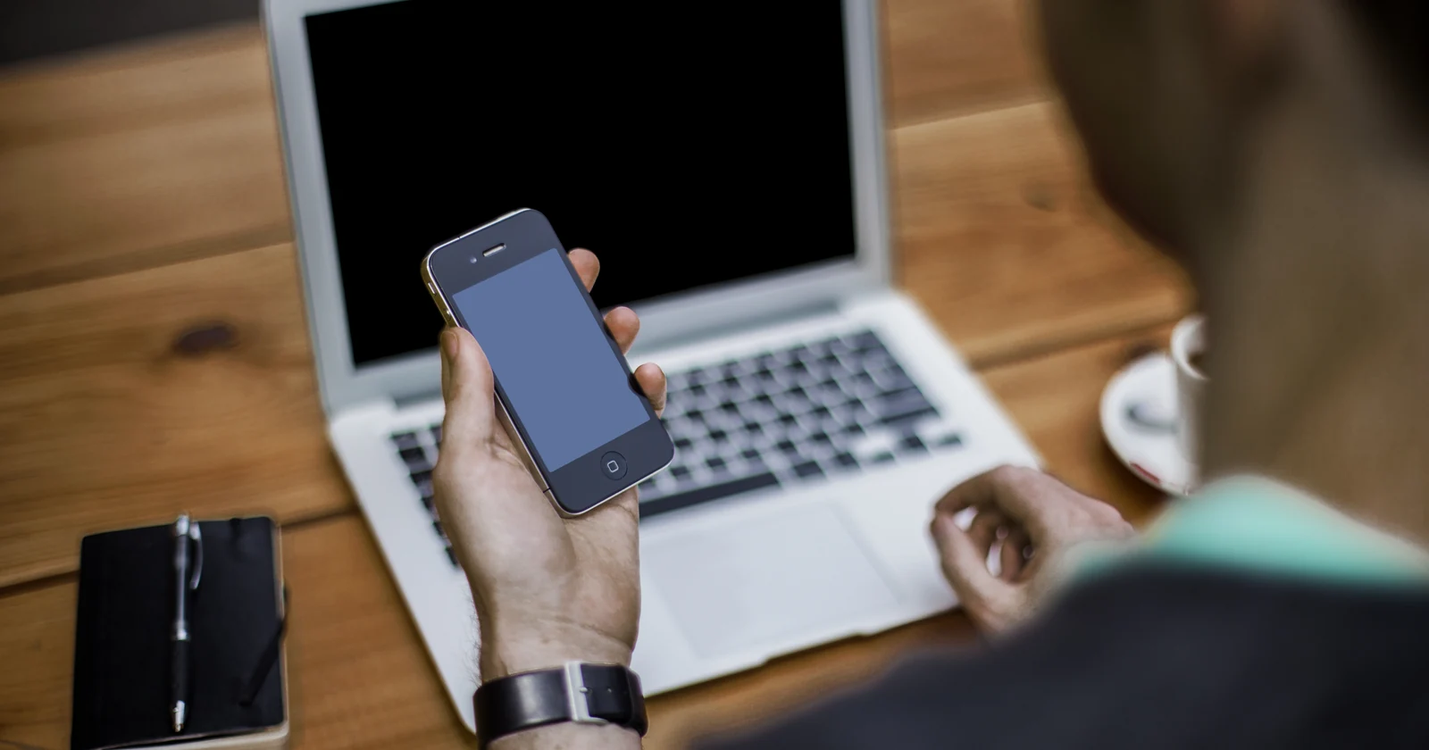 Person using a smartphone beside a laptop