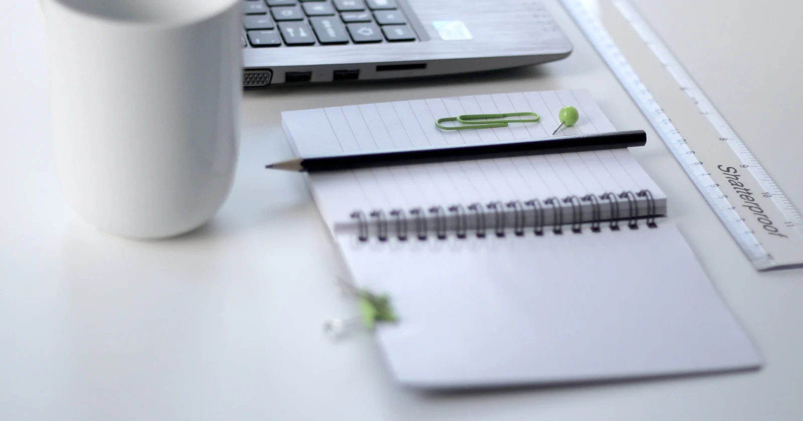 Laptop, notebook and pen on an office work surface