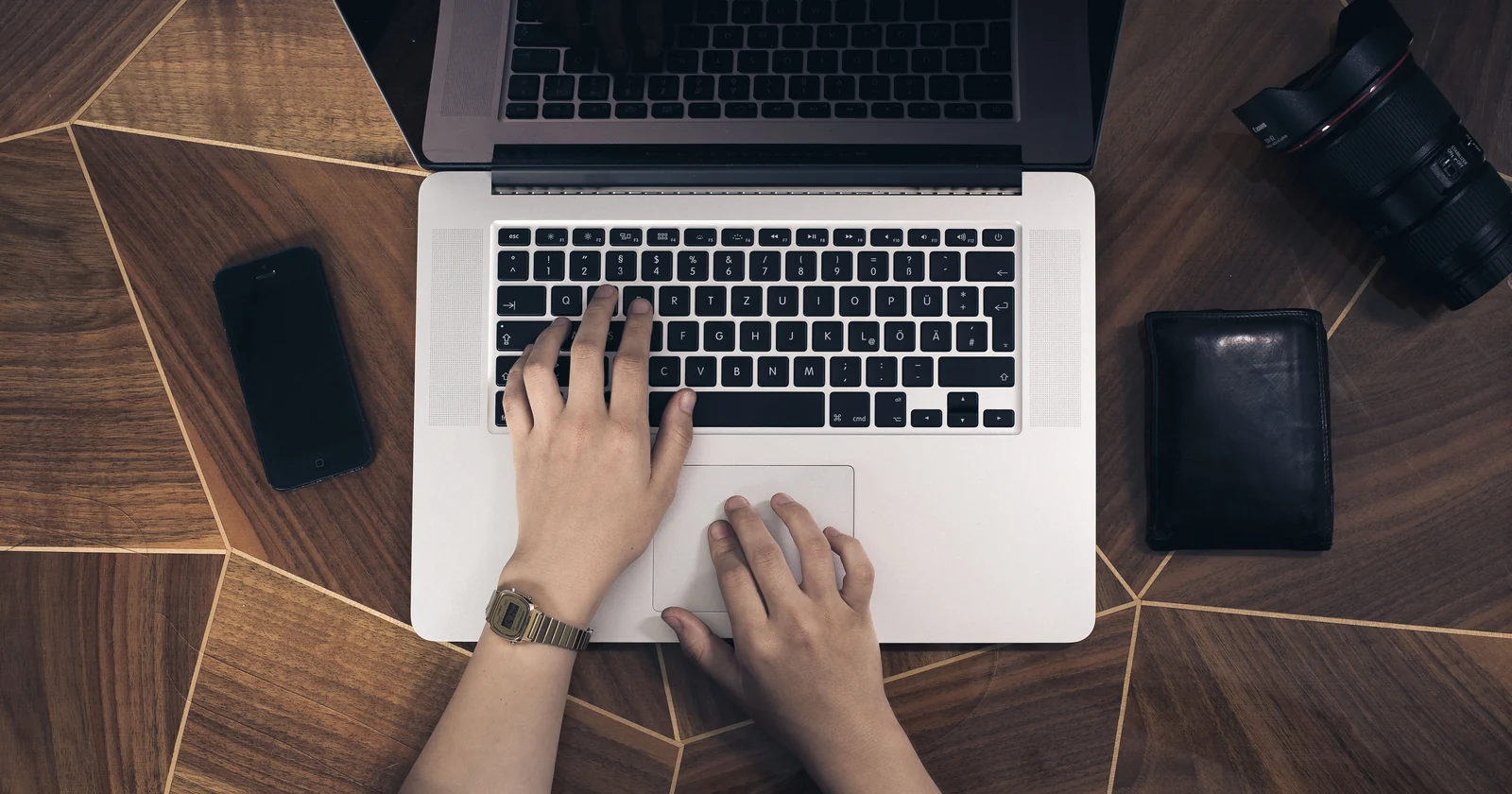 Hands working on a laptop at a wooden desk